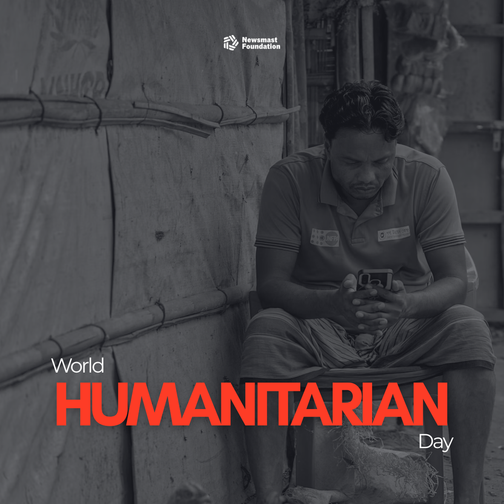 A black and white photo of a man wearing a UNFPA t-shirt sat outside a makeshift shelter, looking at his mobile phone.

Over the image, text reads: Newsmast Foundation. World Humanitarian Day.