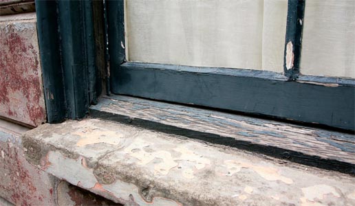 A worn wooden window frame and stone sill A worn wooden window frame and stone sill