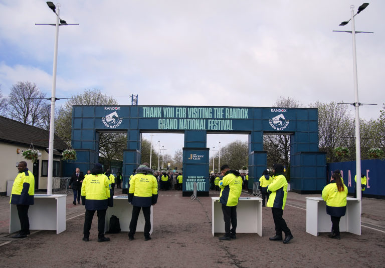 Stewards on an entrance wait for racegoers during day one of the Randox Grand National Festival at Aintree Racecourse