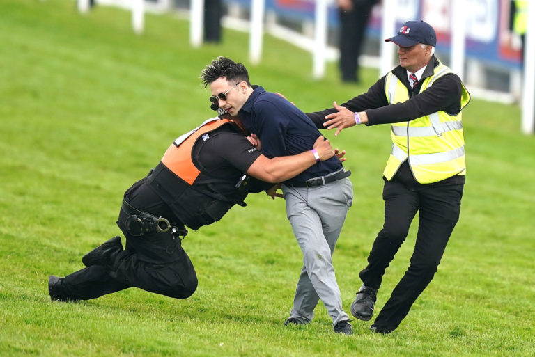 A protestor is tackled by police and stewards