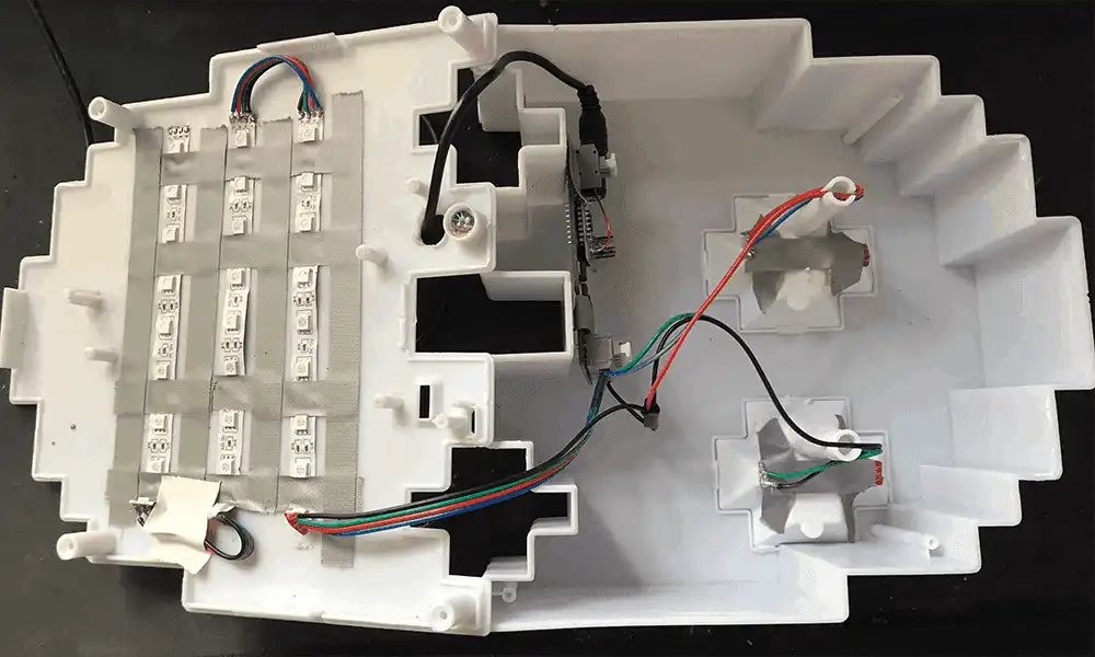 Photograph of open PAC-MAN Ghost containing custom innards with taped down LED strips and Zigbee Controller board. 