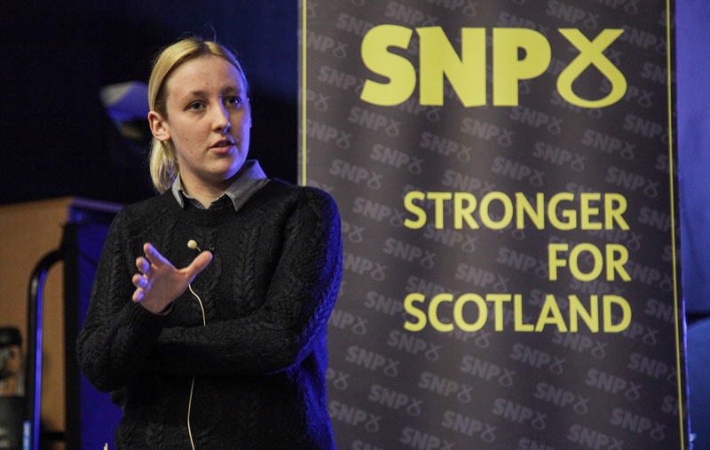Mhairi Black talking in front of an SNP banner