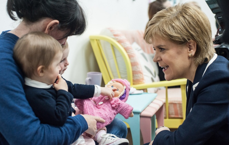 Nicola Sturgeon with some babies being held by a woman