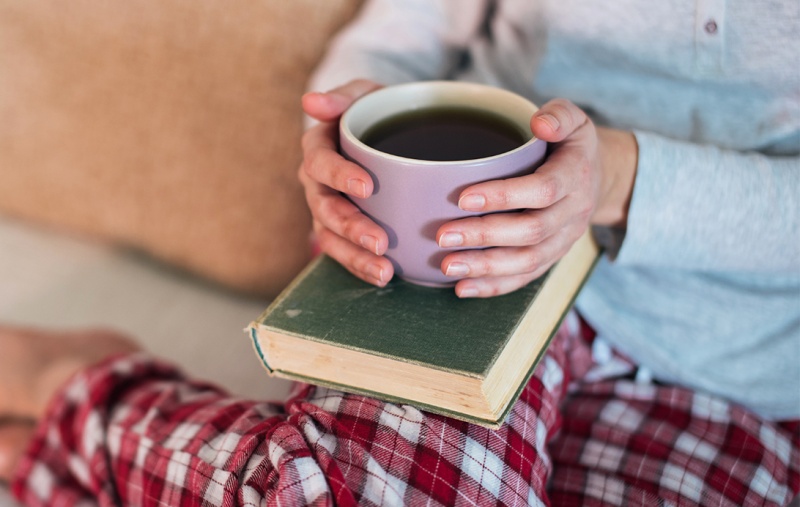 A person in their pyjamas holding a warm drink