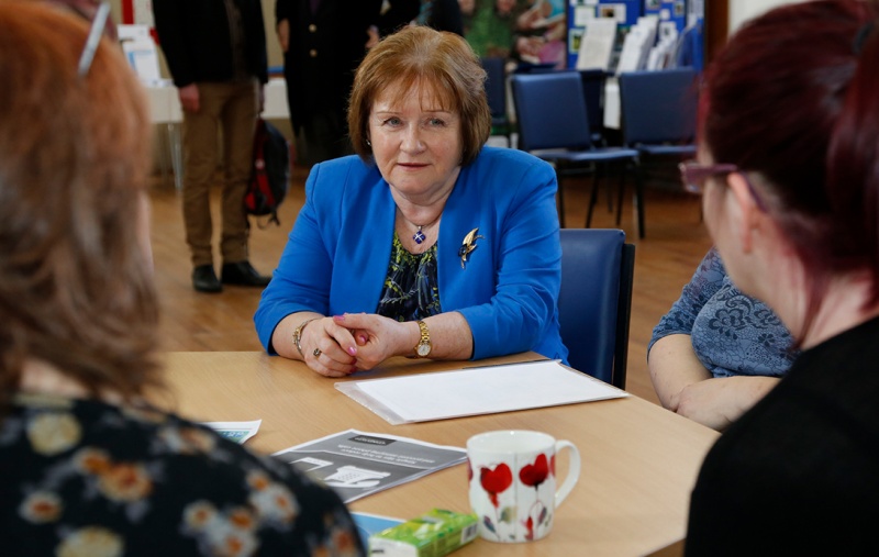 Maureen Watt sitting at a table talking to people