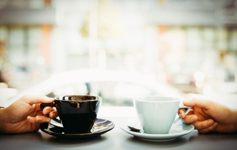Two people holding cups of coffee in a cafe