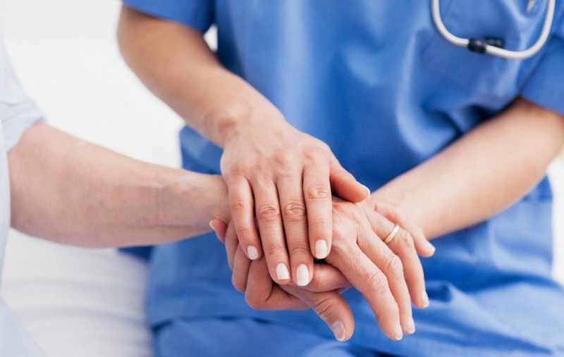 Close up of a nurse touching hand of a patient in hospital ward