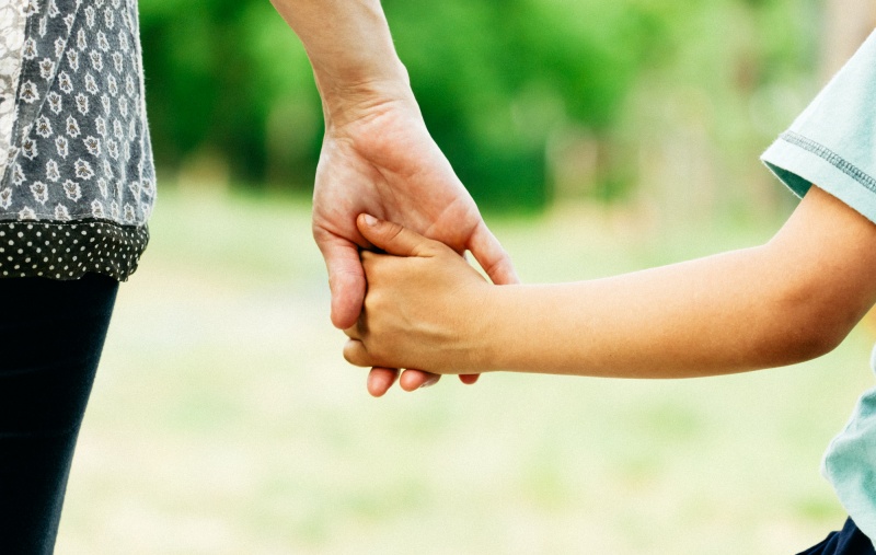 A parent holding their child's hand