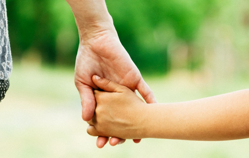 A parent holding their child's hand