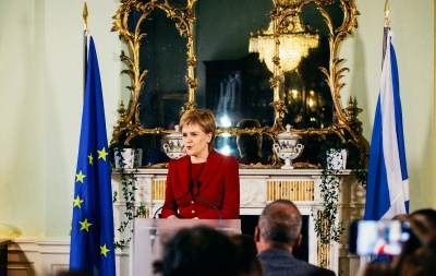 Nicola Sturgeon delivering a speech in Bute House with the EU and Scottish Flags behind.
